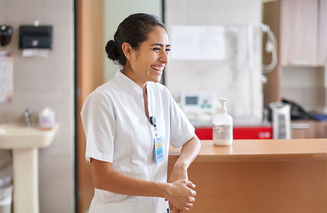 Nurse standing by desk, laughing.